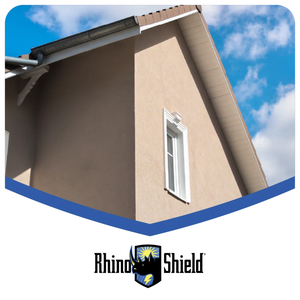 A close-up of a stucco house with Rhino Shield branding, showcasing a durable exterior finish